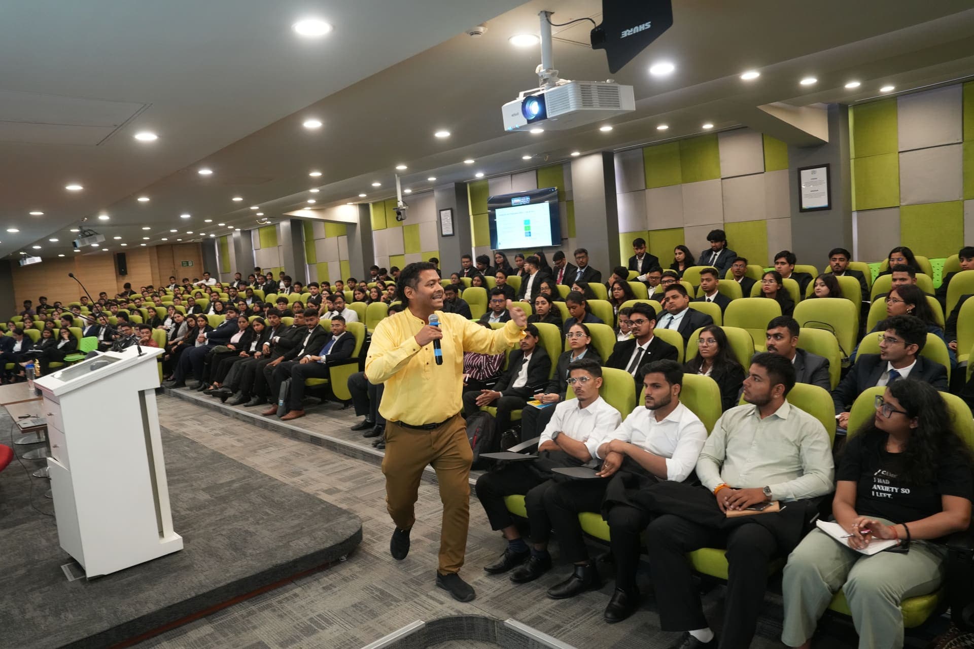 Dr Swapnil Sahoo speaking energetically to a full auditorium during a PGDM induction session