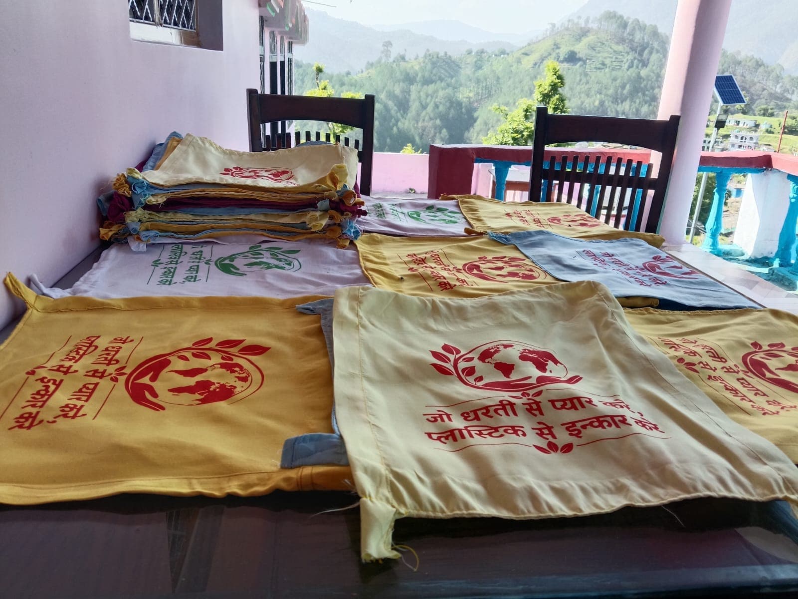 Repurposed cloth carry bags printed with an anti-plastic message, laid out ready for distribution in Mehalchauri