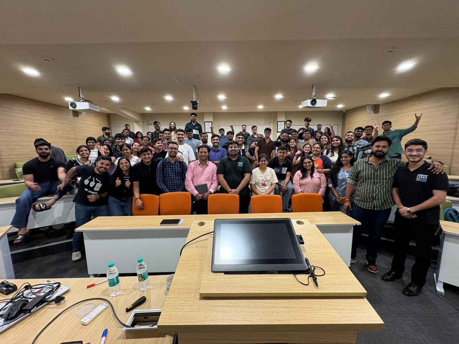 A Strategy cohort gathered for a joyful group photo in the lecture hall, several wearing Great Lakes branded shirts