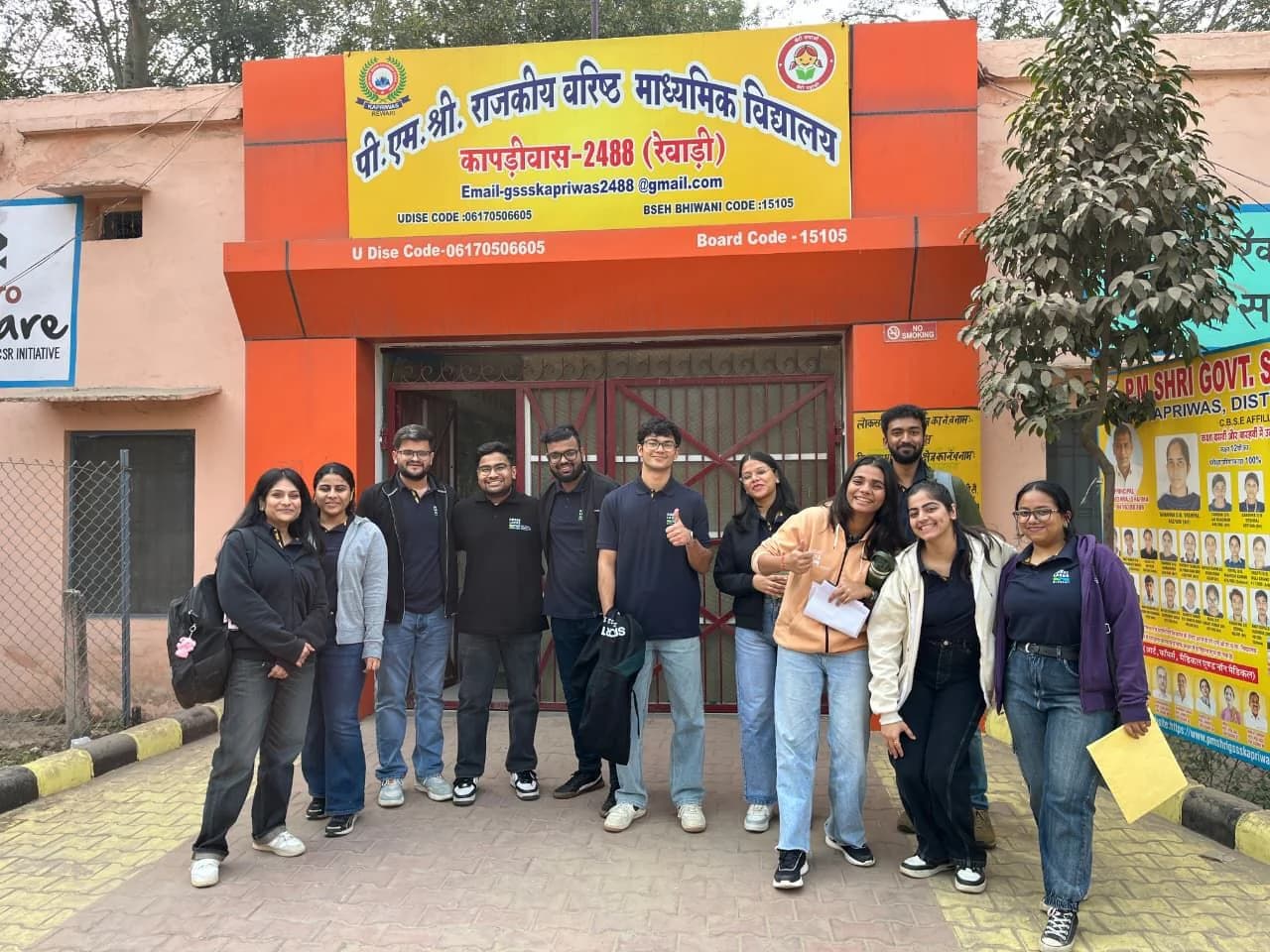 A management student field team standing together outside a government school