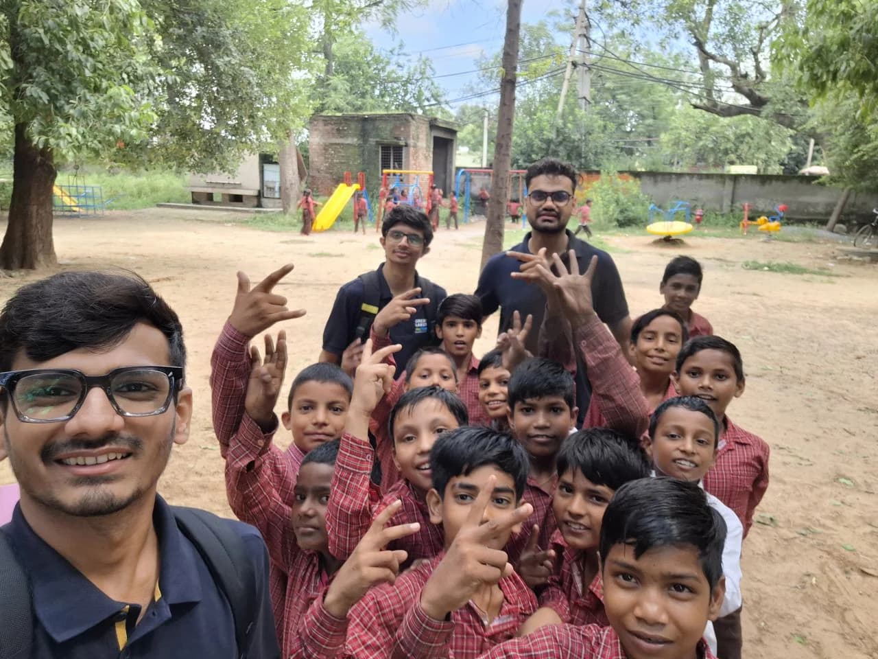 Management students taking a cheerful group photograph with schoolchildren outdoors