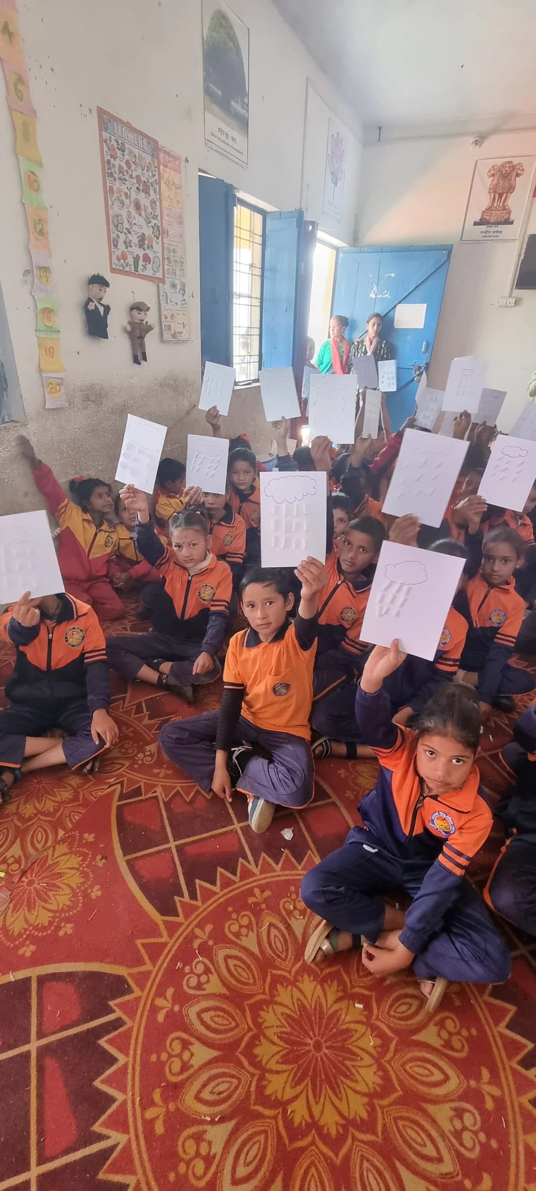 Children at Saraswati Shishu Mandir holding artwork from a clouds and rain workshop