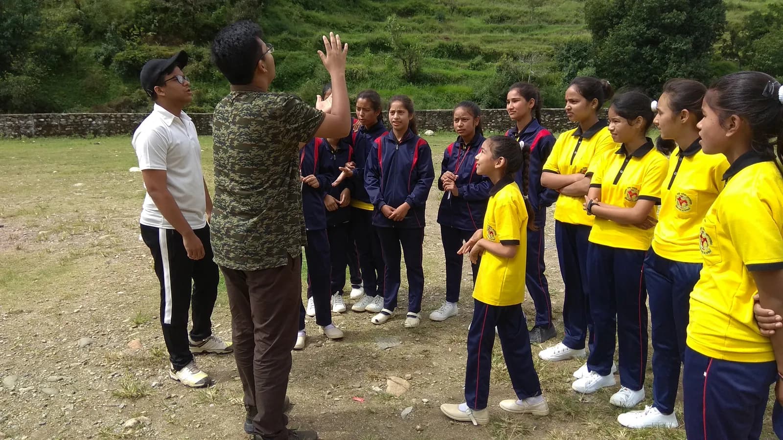 Girls in sports uniforms gathered with programme facilitators on a Himalayan playing field