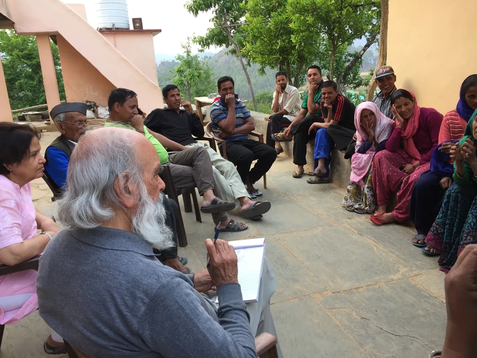 Village residents and programme partners seated together in a courtyard discussion