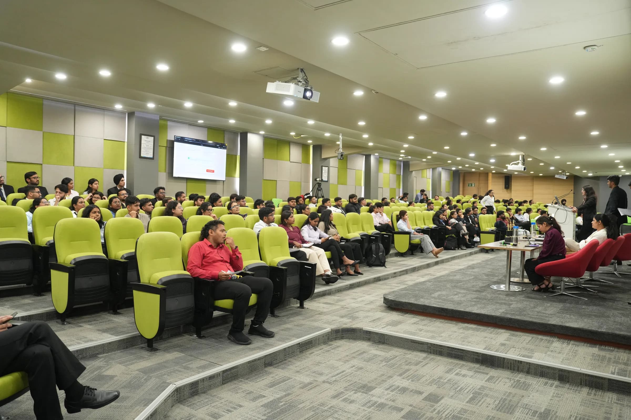 A packed lecture hall of incoming PGPM 2026-27 students during induction, with faculty at the front of the room