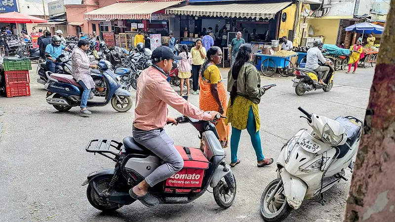 A Zomato delivery partner riding a Yulu bike on a Bengaluru street.