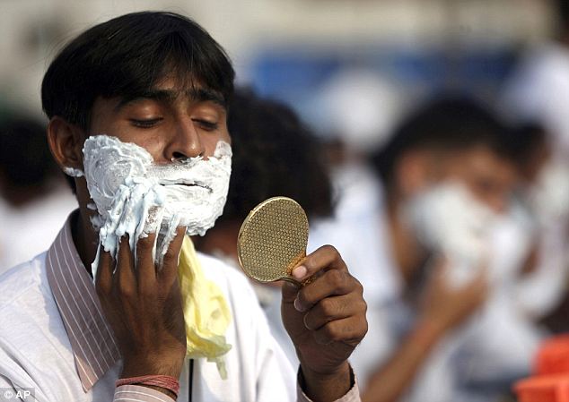 Indian man shaving with a handheld mirror
